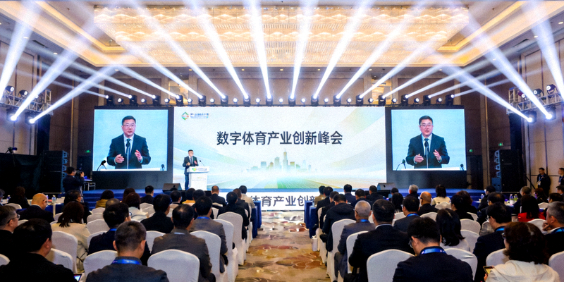 数字体育产业创新峰会主会场全景 - 行业领袖在聚光灯下演讲，台下坐满参会者，大屏幕显示峰会主题