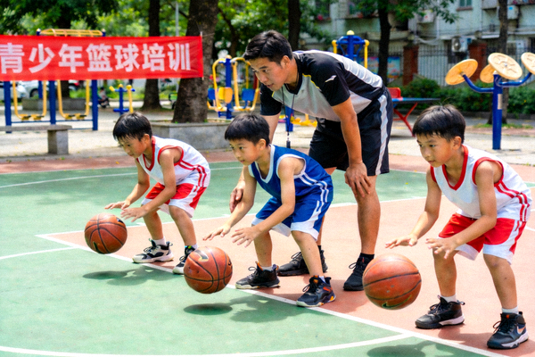 广州社区篮球场青少年篮球培训课，教练正在指导孩子们运球